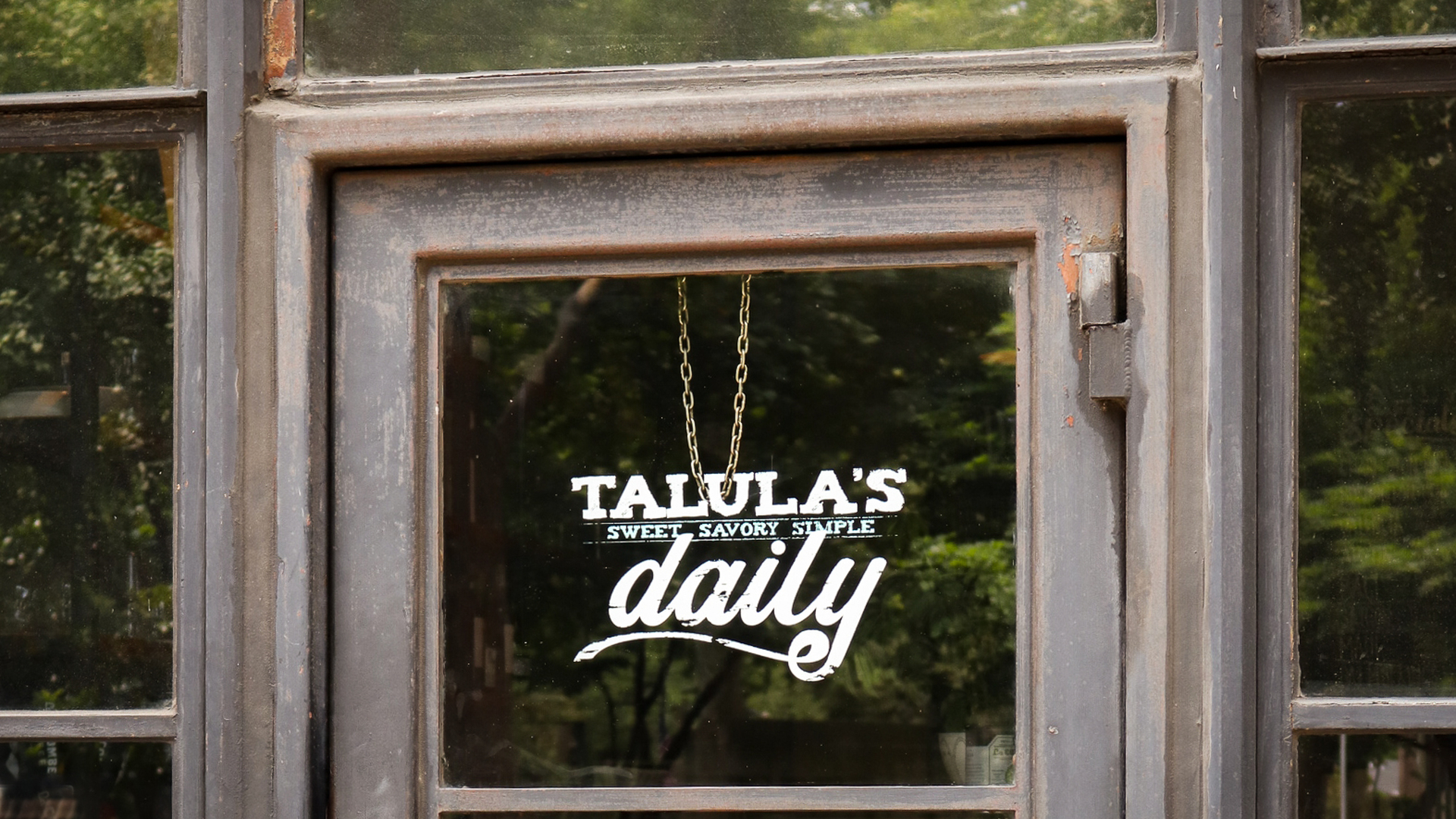 Restaurant sign window "Talula's Daily Sweet Savory Simple" on weathered wooden door.
