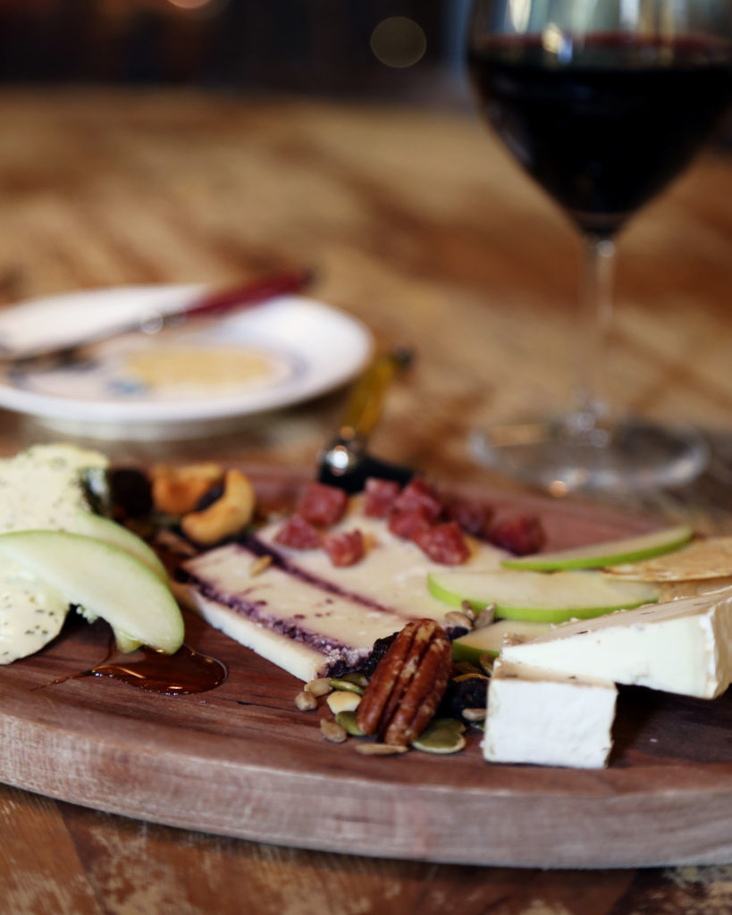 A cheese board with a glass of red wine